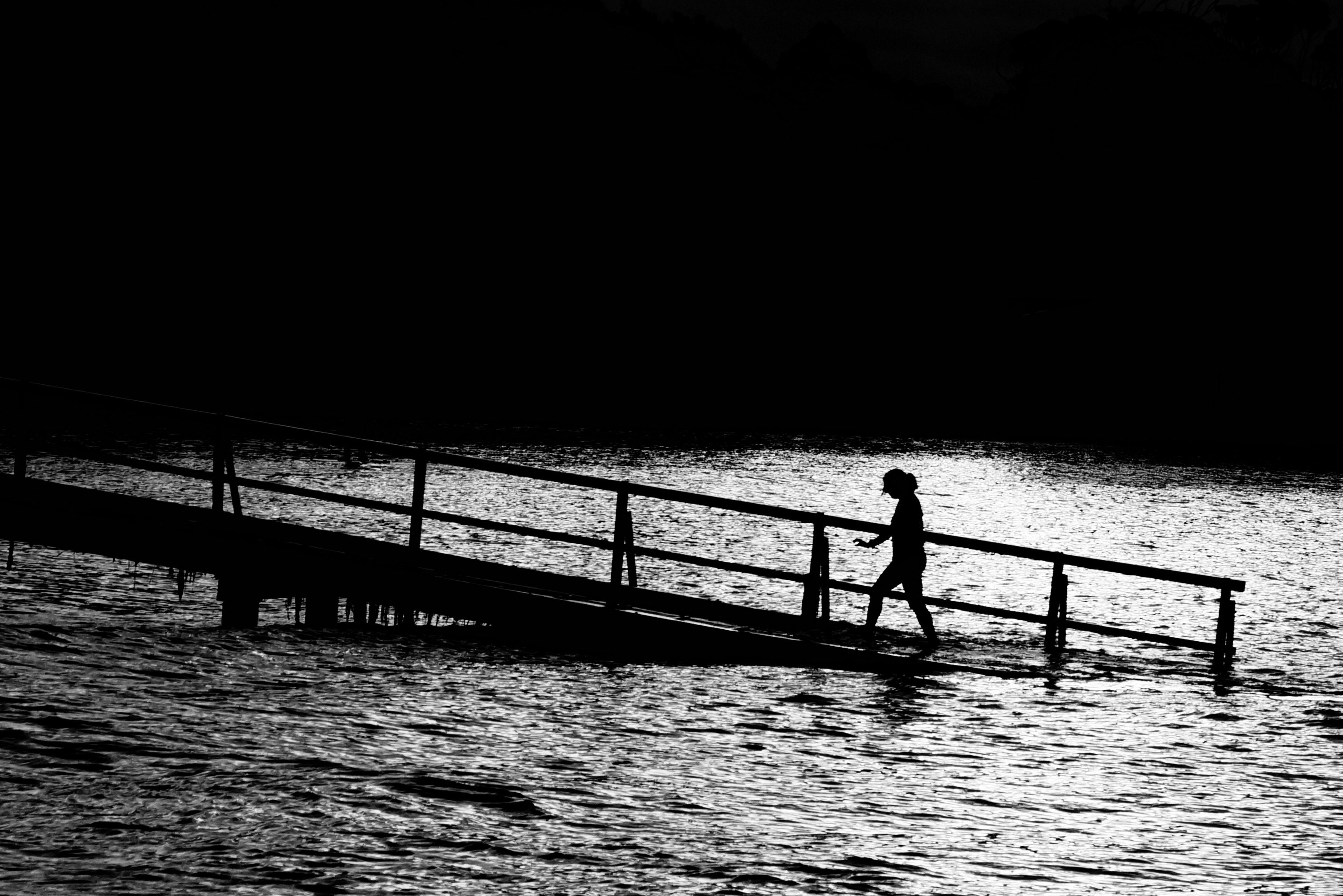 person walks on brown pier over body of water